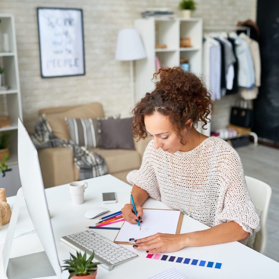 High angle portrait of modern creative woman working at desk choosing color palette for interior design and making notes